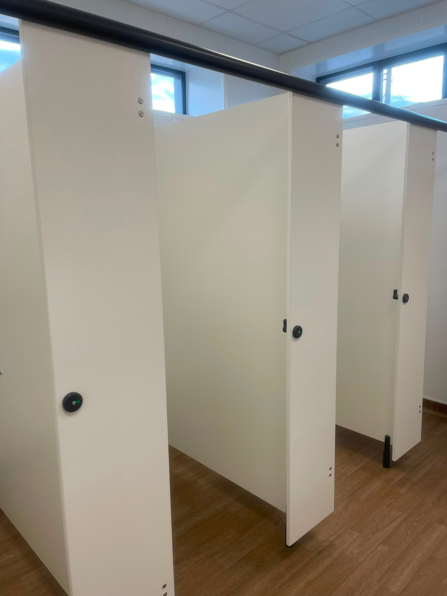 Newly installed washroom cubicles with timber-effect flooring