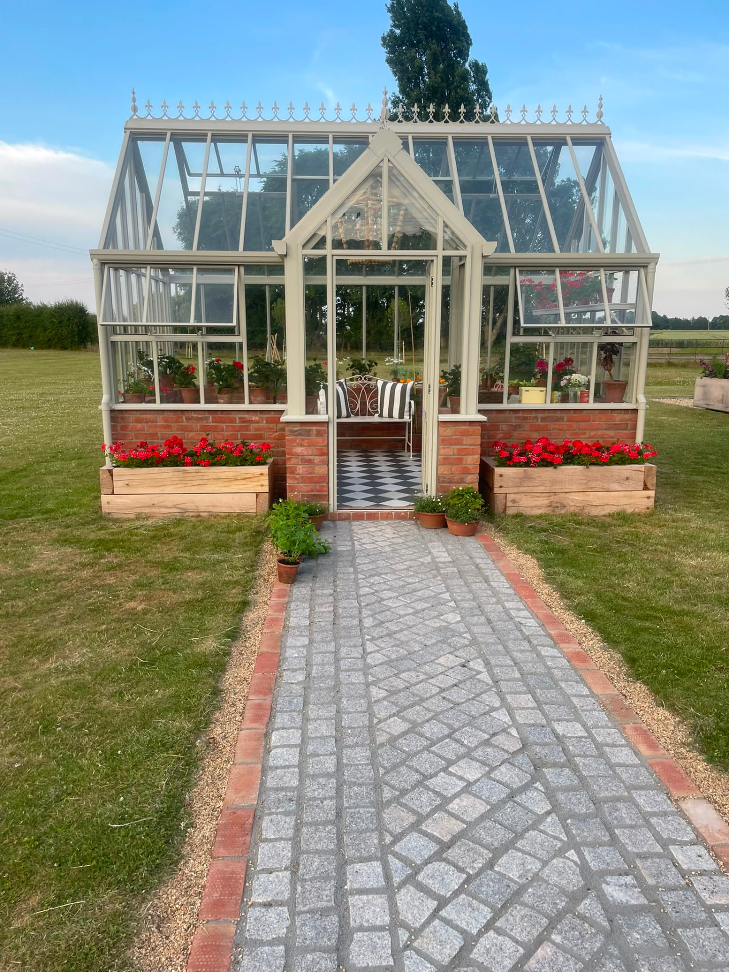 Victorian-style glasshouse with brick base and granite setts path