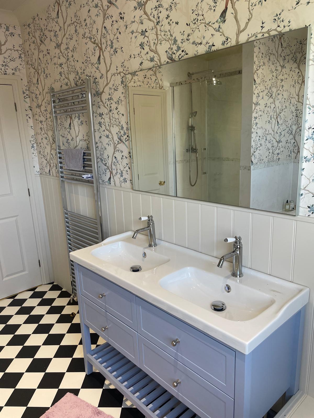 Newly fitted bathroom with a light blue double vanity, chrome taps and heated towel rail