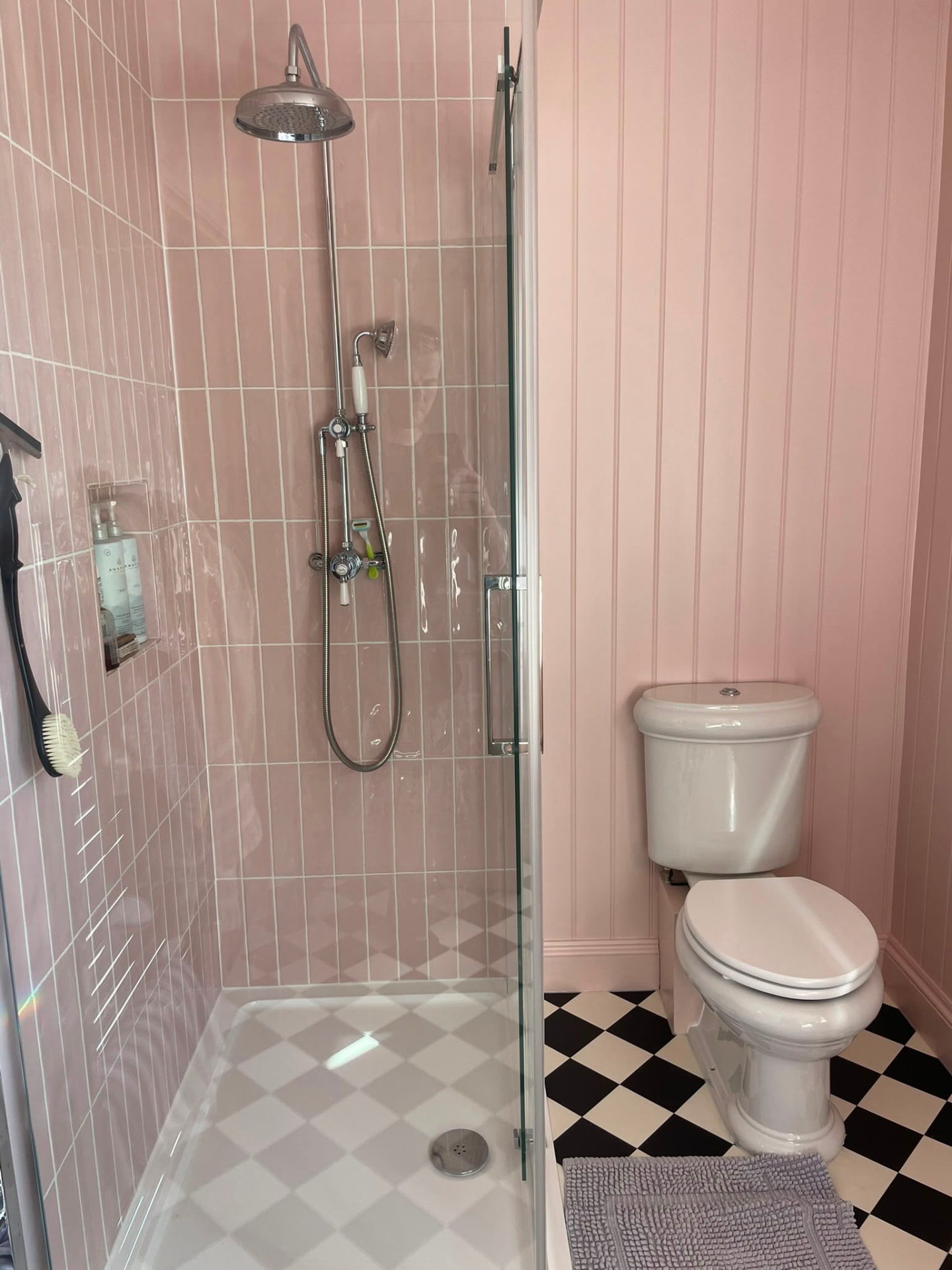 Pink tiled shower room with rainfall shower and chequerboard floor