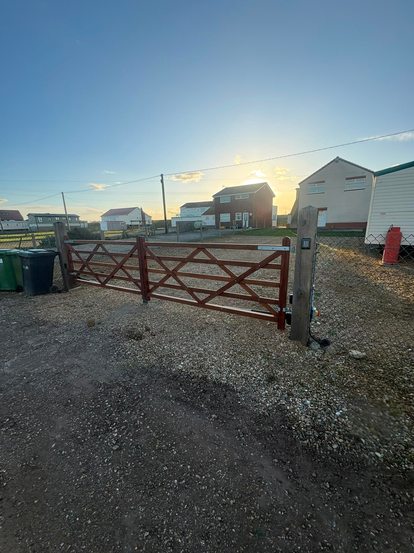 Automated five-bar timber entrance gate on a gravel drive