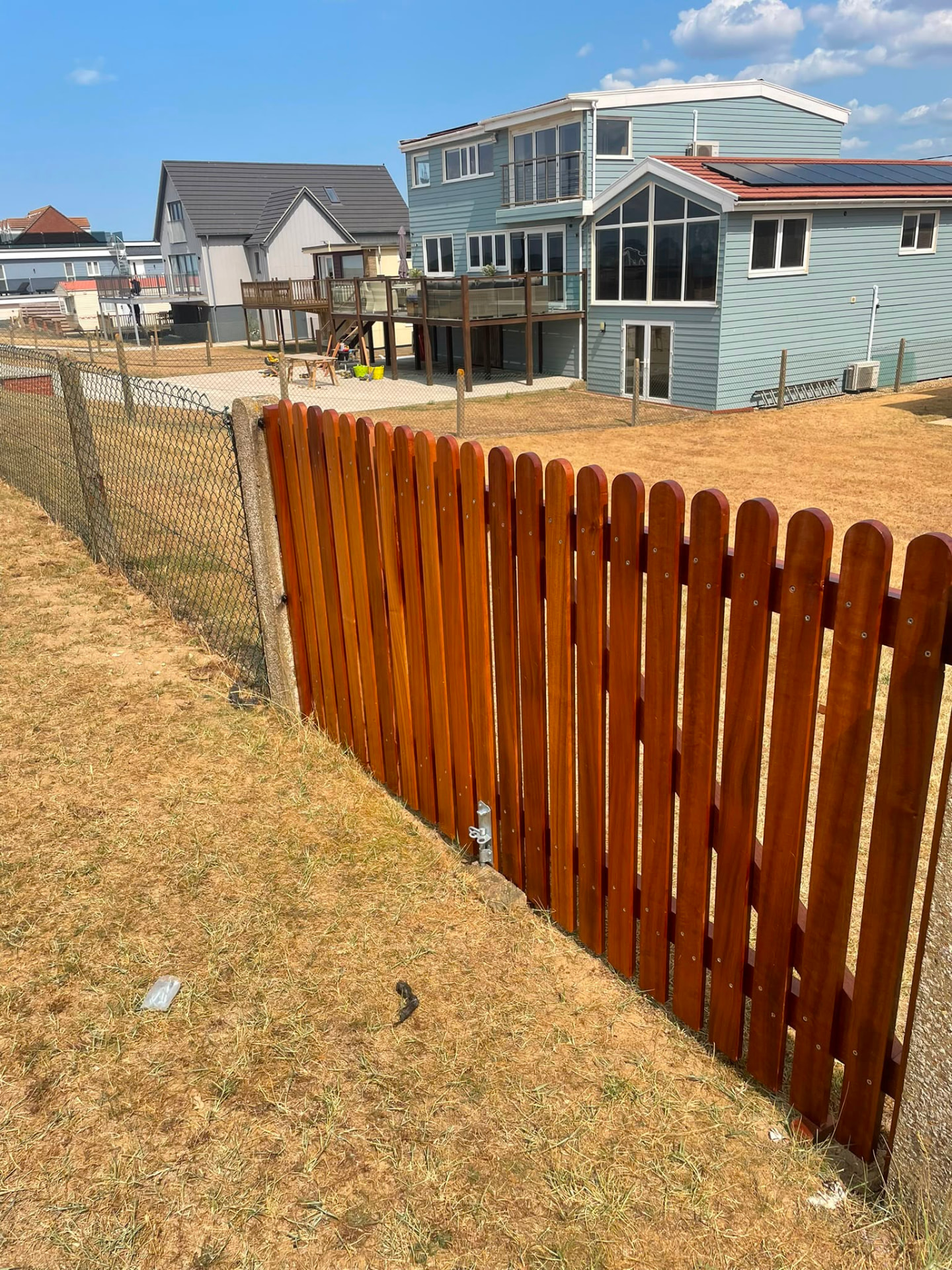 Stained round-top picket fencing to a coastal property