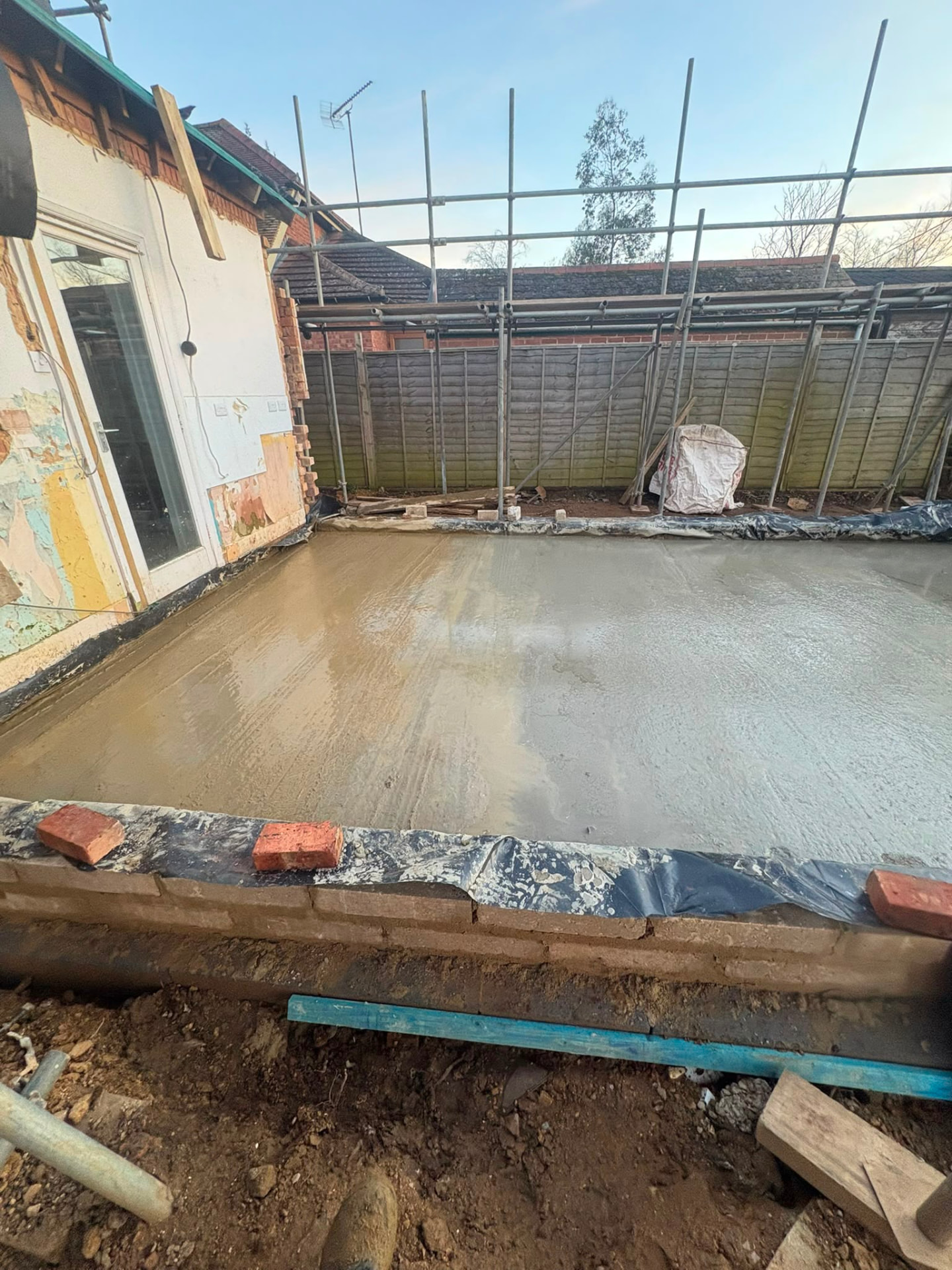 Concrete base and foundations being laid on a residential building site with scaffolding